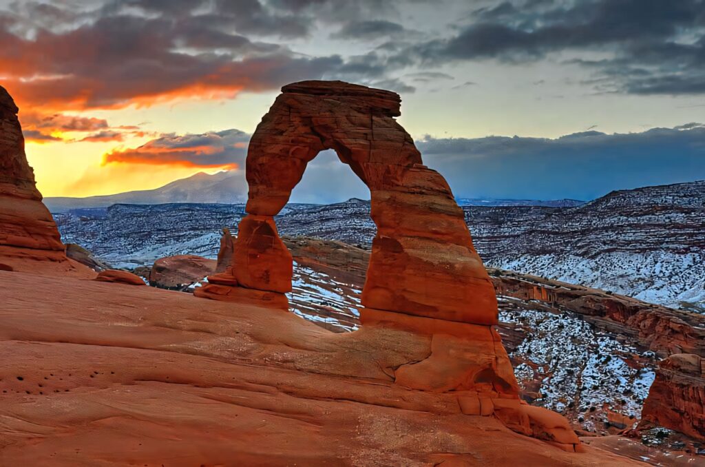 Delicate Arch at sunset with red sandstone glowing against vivid orange and blue sky background Wallpaper