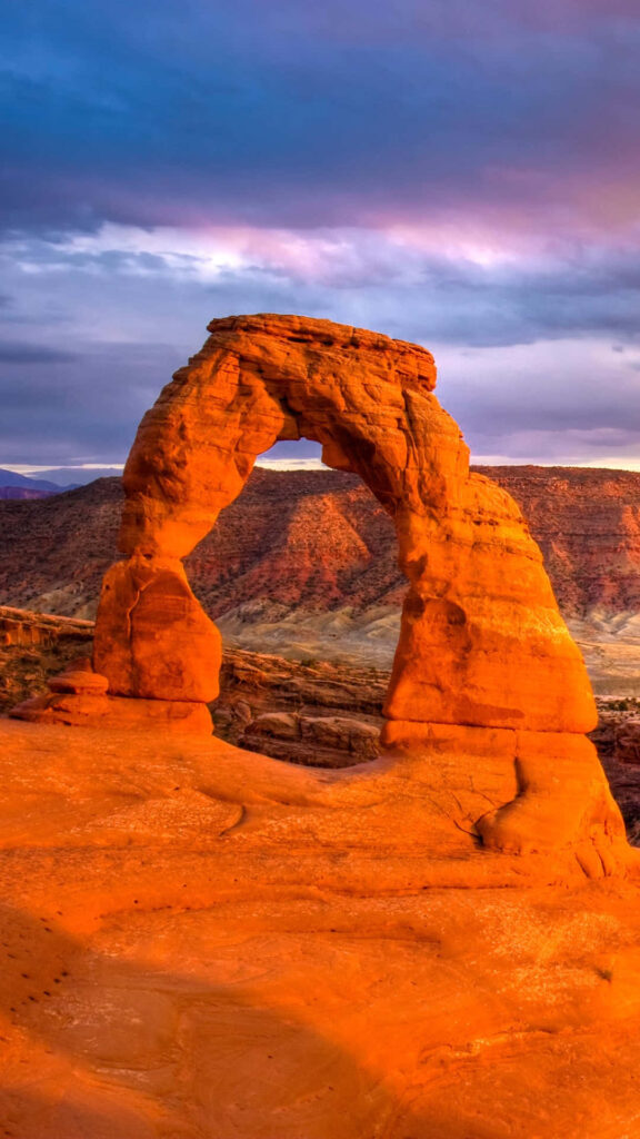 Delicate Arch at sunset glowing orange with sandstone texture and colorful dramatic sky background Wallpaper