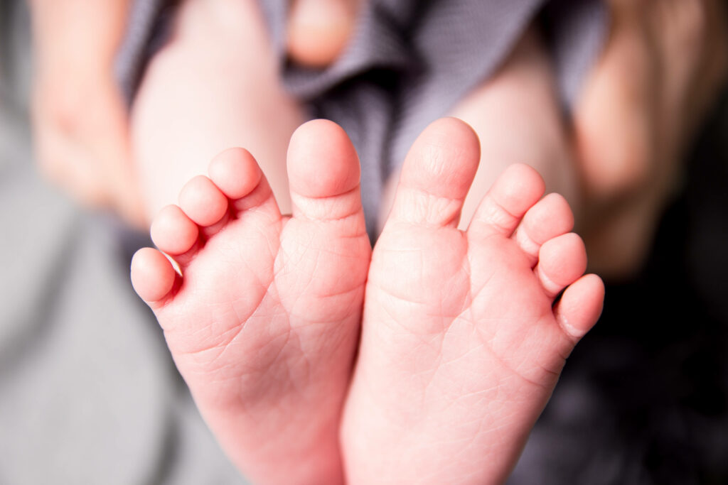 Close up of delicate soft baby boy feet on wallpaper background for newborn photography