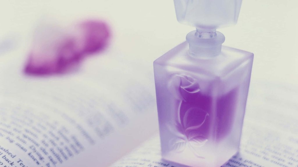Lavender perfume bottle with rose engraving on open book soft-focus romantic fragrance wallpaper