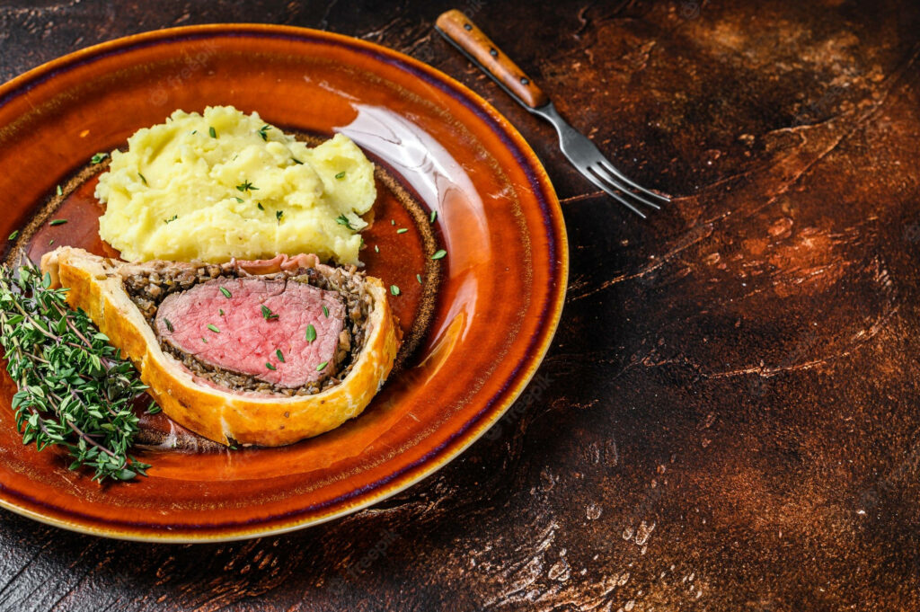 Beef Wellington with golden crust creamy mashed potatoes fresh herbs on rustic ceramic plate wallpaper