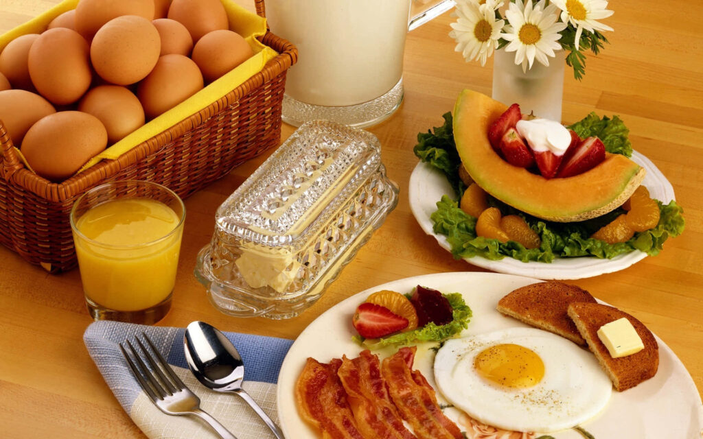 Delicious Breakfast Spread: Eggs, Bacon, Toast & Fresh Fruits Wallpaper