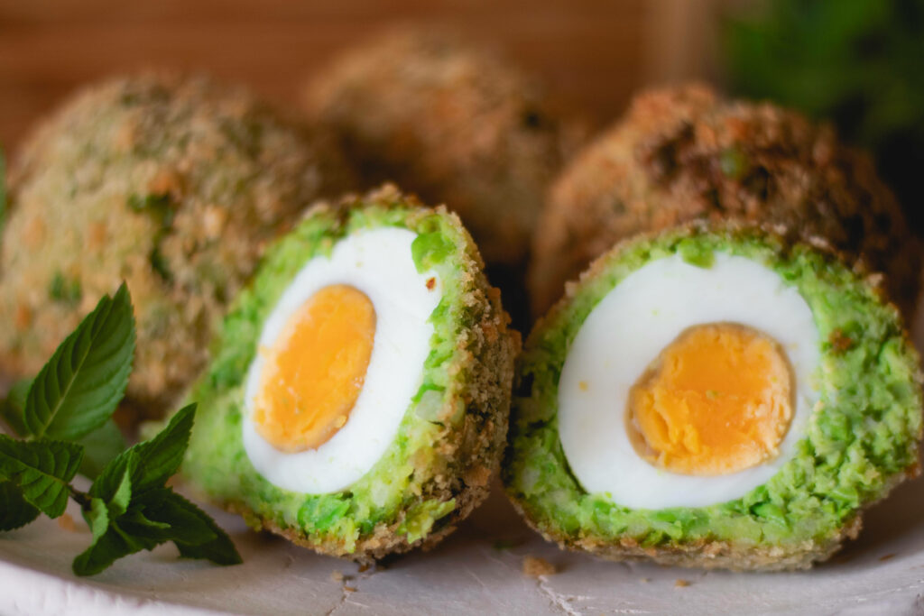 Rustic Scotch Eggs: Avocado-Wrapped Delight on a Charming Plate Wallpaper