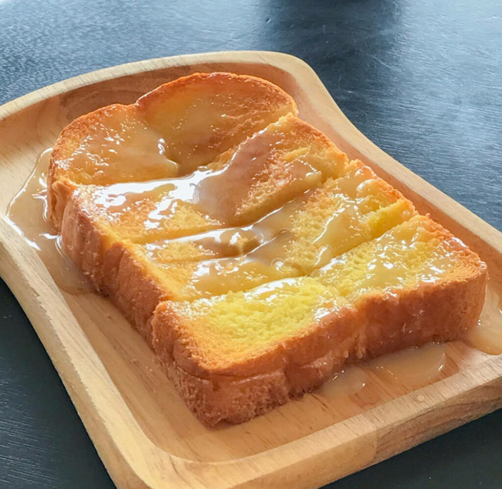 Close-Up of Melted Buttered Toast on Wooden Tray - Wallpaper Background