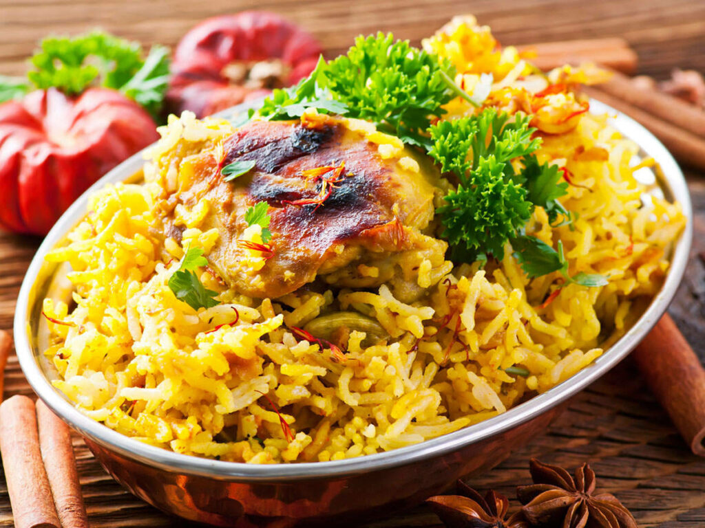 Chicken biryani with tender spiced chicken and vibrant yellow rice garnished with fresh herbs wallpaper