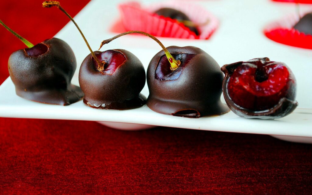 Delicious Chocolate-Covered Cherries: Vibrant Red Wallpaper Background