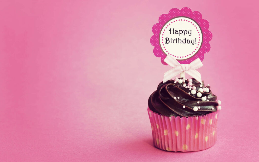 Charming birthday cupcake with chocolate frosting colorful sprinkles on vibrant pink background Wallpaper