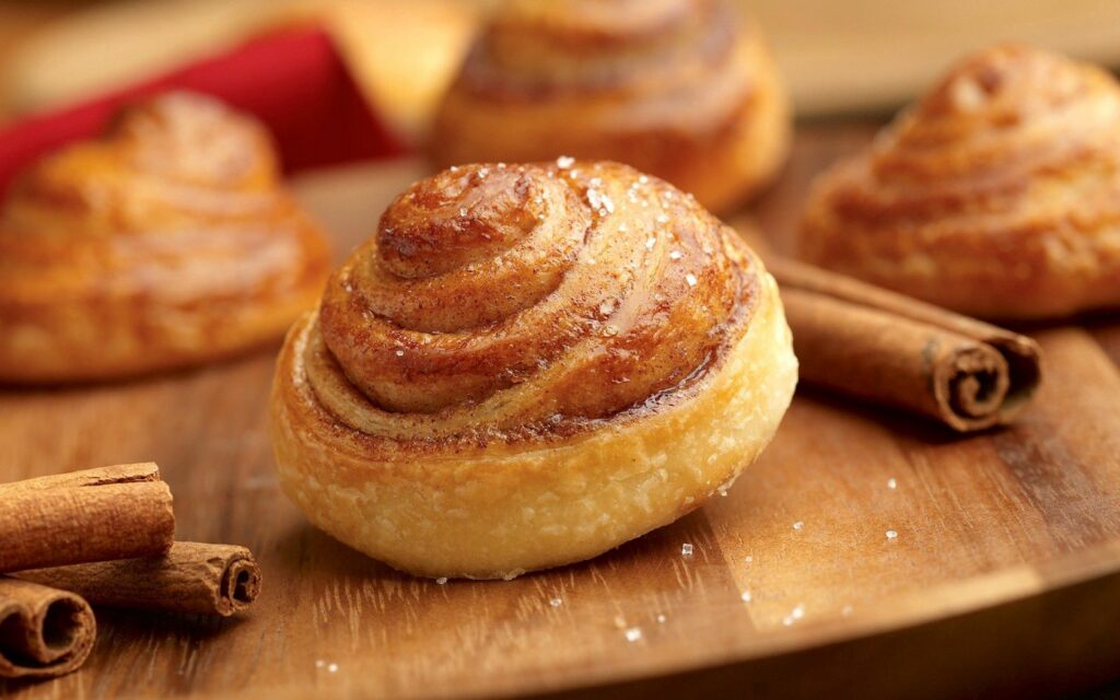 Golden-Brown Cinnamon Buns with Sugar & Cinnamon Sticks Wallpaper
