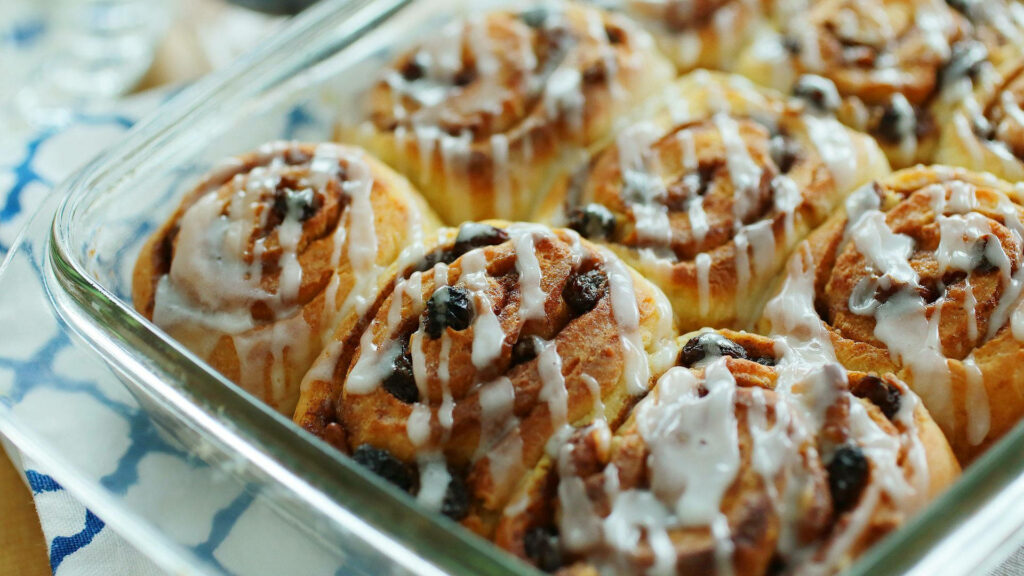 Fresh Cinnamon Rolls Wallpaper: Sweet Icing & Raisins in Glass Dish