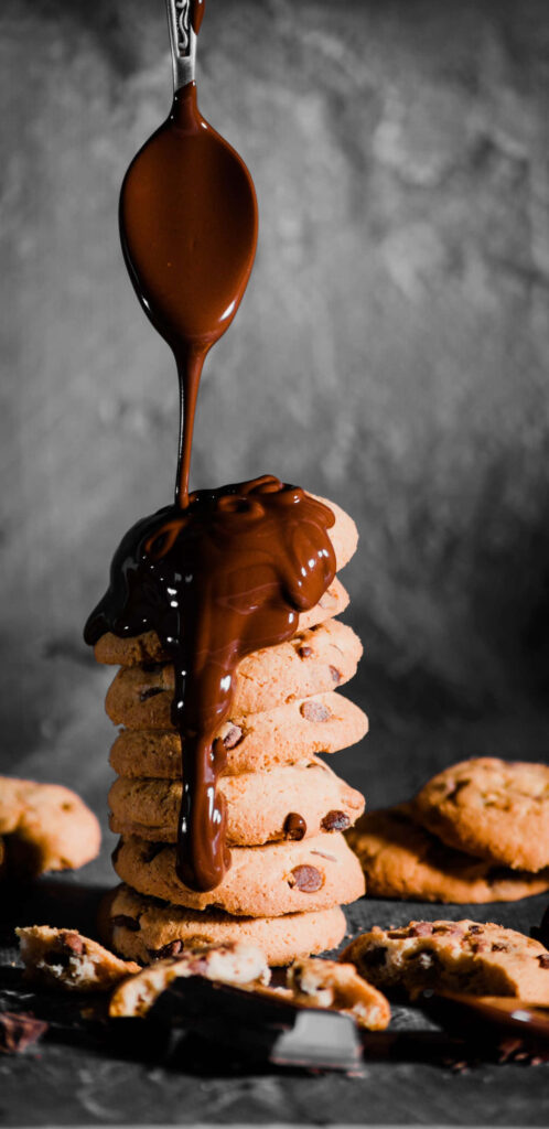 Tempting Chocolate Cascades over Delectable Choco Chip Cookies amid Industrial Chic Wallpaper