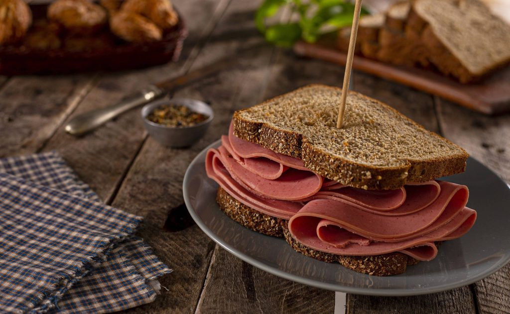 Deli meat sandwich on multigrain bread on gray plate rustic wooden background wallpaper