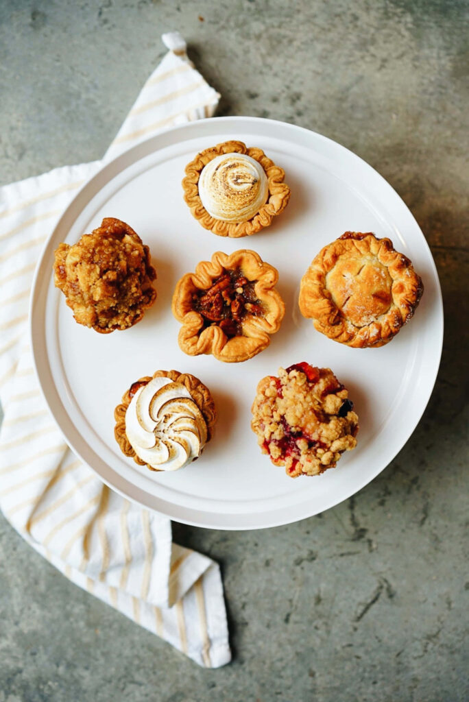 Decadent Delights: A Scrumptious Assortment of Tempting Brown Tarts on a Luscious White Tray Wallpaper