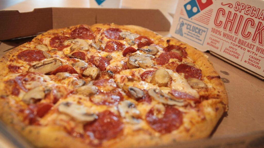 Fresh Domino's pepperoni and mushroom pizza with golden cheese in an open box background Wallpaper