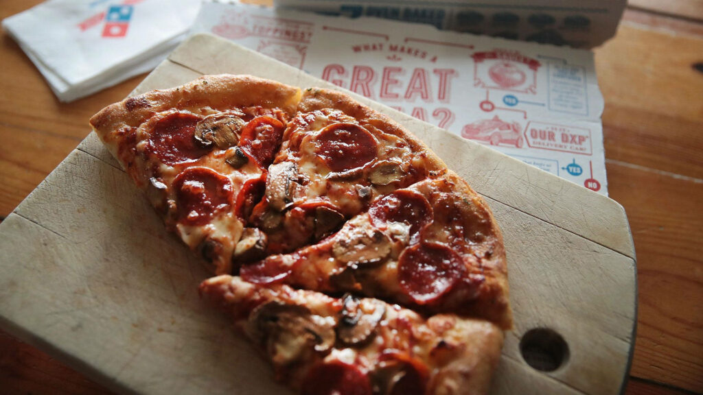 Slice of Domino's pepperoni mushroom pizza on wooden board warm natural light rustic table Wallpaper