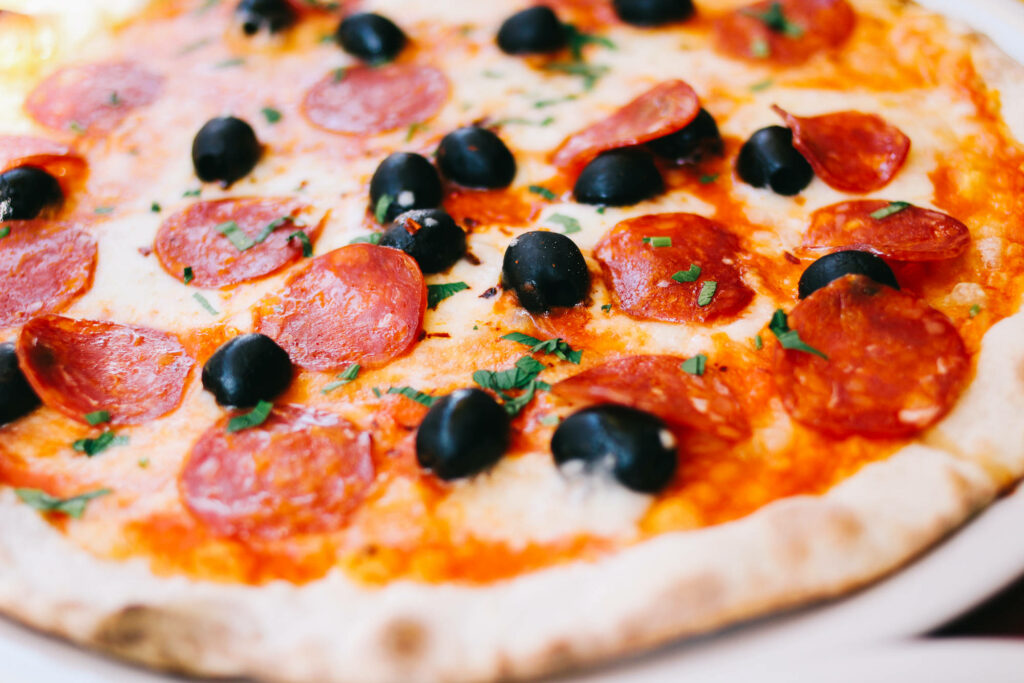 Close-up of Domino's pizza with pepperoni olives melted cheese herbs on crispy golden crust wallpaper