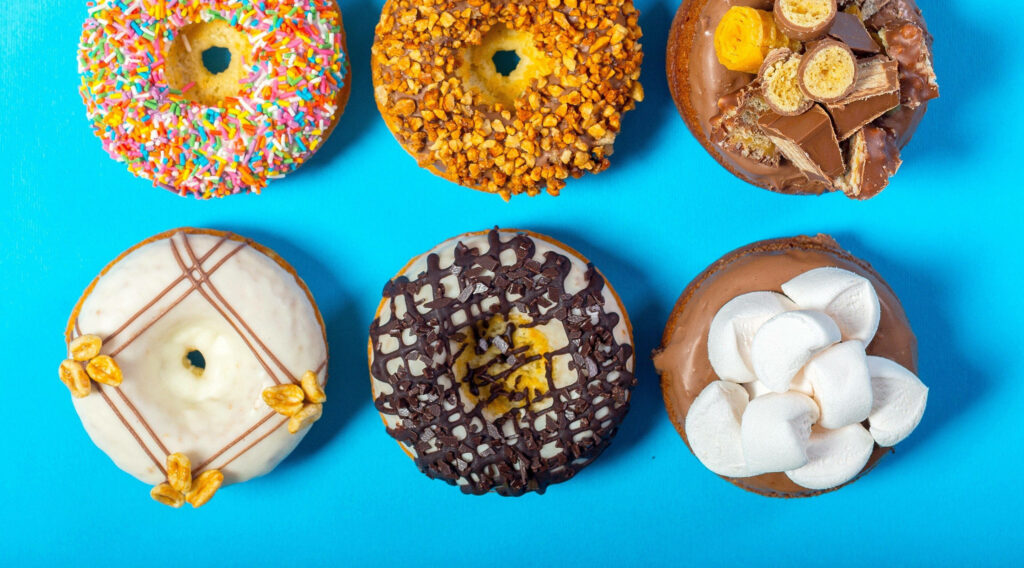 Donut Delights: A Tempting Array of Sweet Treats on a Vibrant Blue Canvas Wallpaper