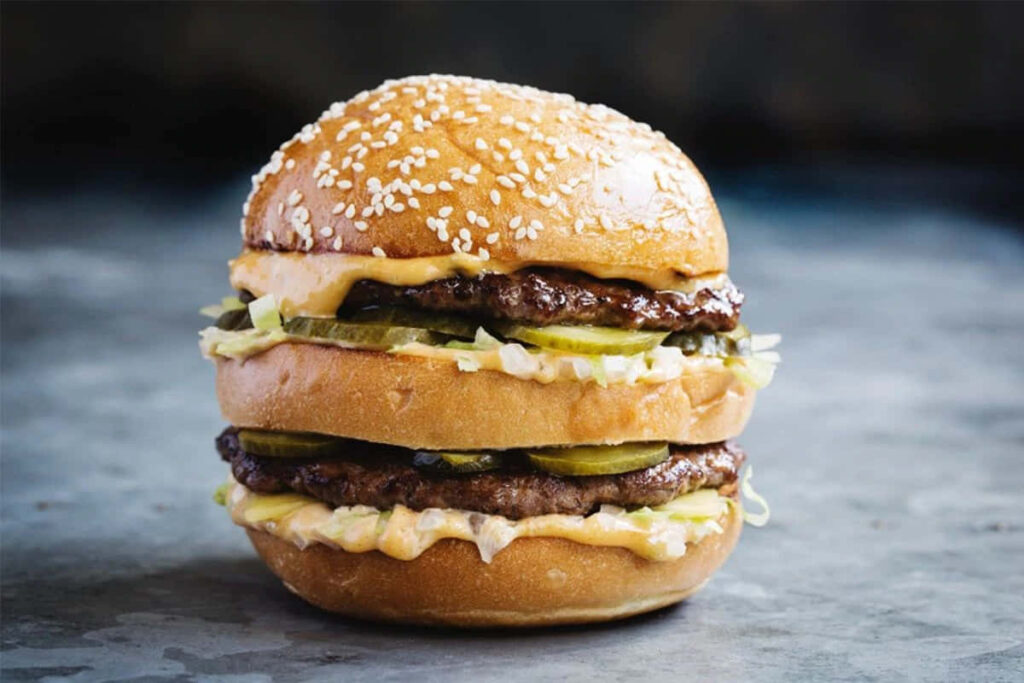 Delicious Double Cheeseburger Wallpaper with Pickles & Sauce