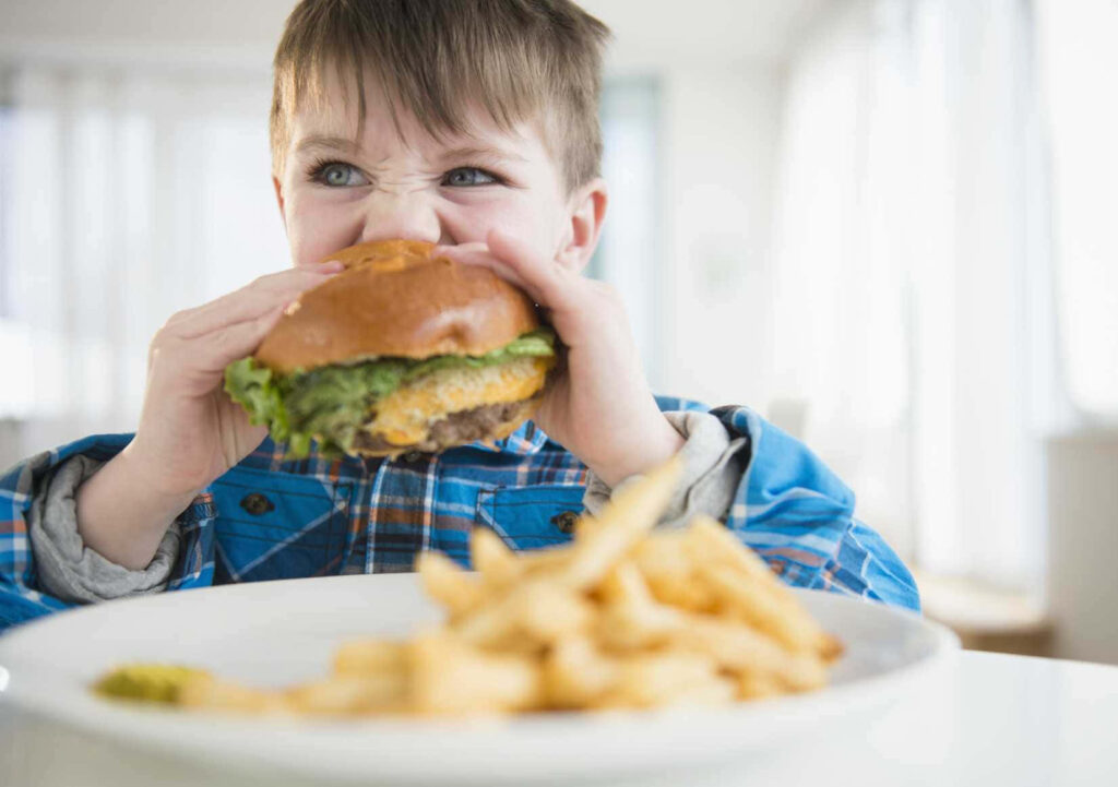 Young Boy's Joy: Delicious Burger & Crispy Fries Wallpaper