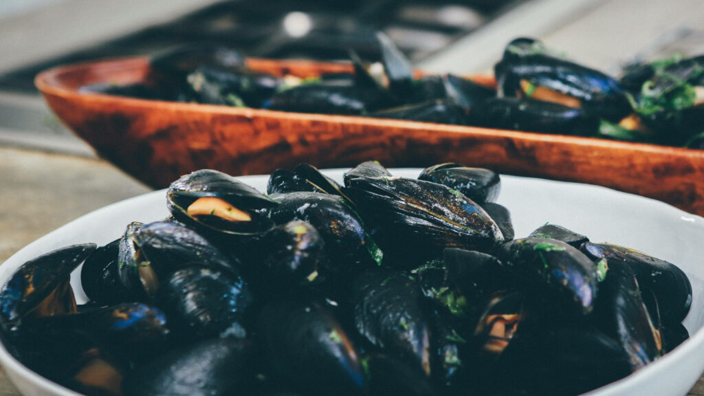 Glossy Garlic Mussels in Bowl - Delicious Close-Up Wallpaper
