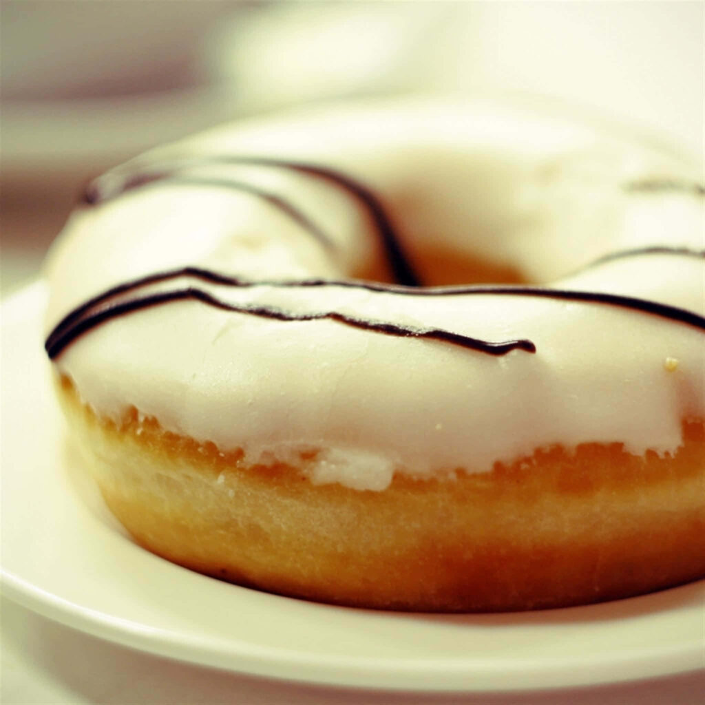 Tempting Chocolate-Drizzled Glazed Donut on White Plate Wallpaper