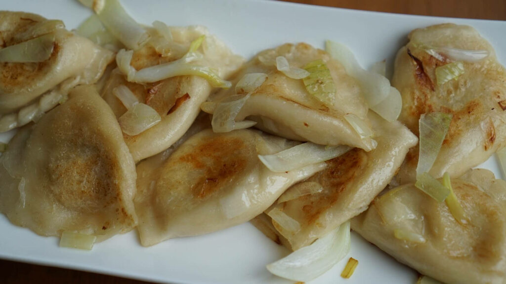 Delicious Golden-Brown Pierogi with Sautéed Onions - Wallpaper Image