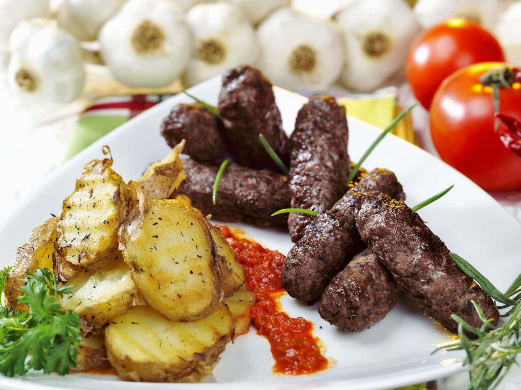 Delicious Grilled Ćevapi Wallpaper with Crispy Potatoes & Red Sauce