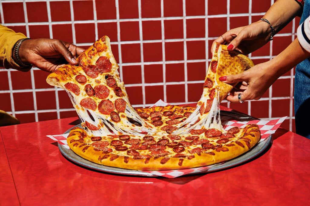 Delicious Pepperoni Pizza with Cheese Against Vibrant Red Wall Wallpaper