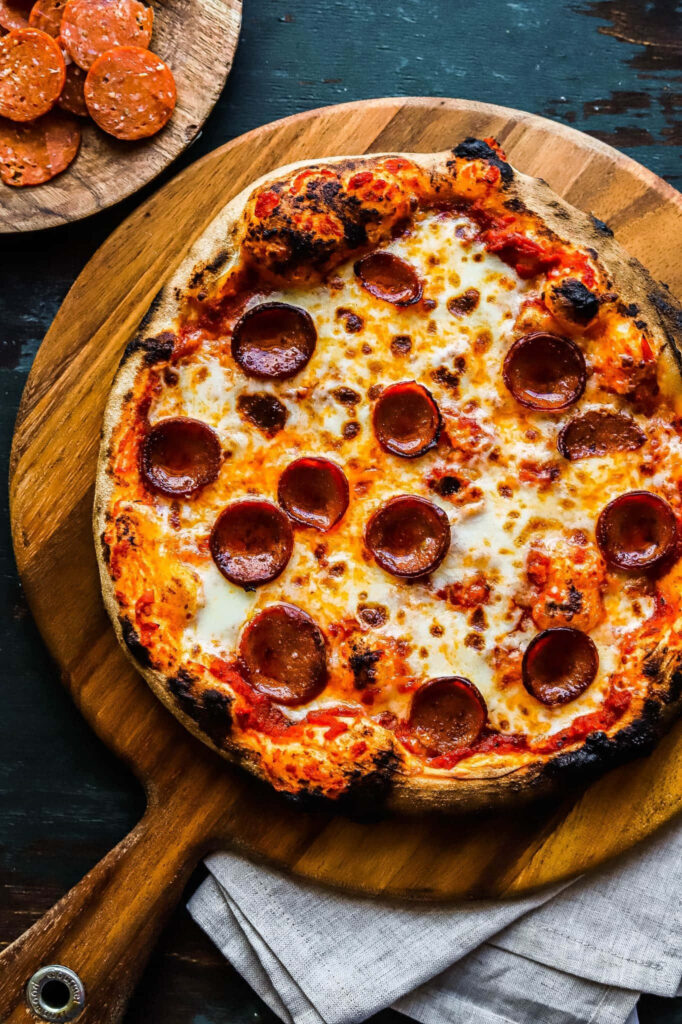 Pepperoni pizza with golden bubbly cheese on wooden board perfect for sharing with friends Wallpaper