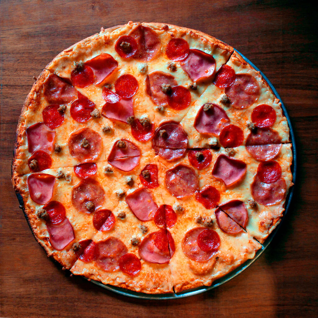 Pepperoni pizza with melted cheese and meat slices on rustic dark wooden surface wallpaper