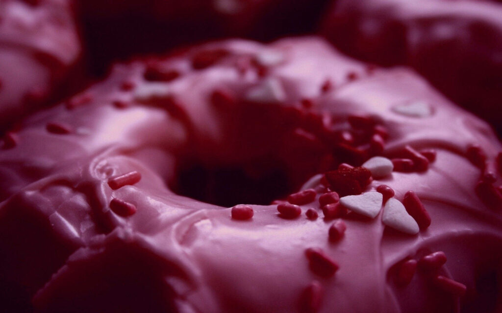 Delicious Pink Iced Doughnut Wallpaper with Heart Sprinkles