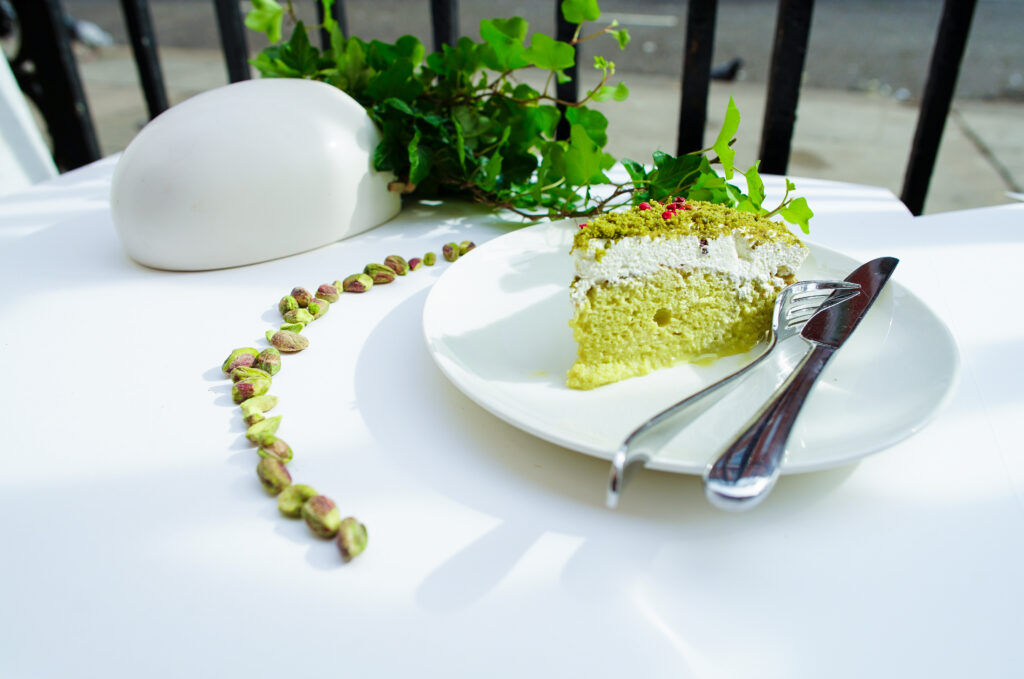 Pistachio Cake Slice with Cream on White Plate - Elegant Dessert Wallpaper