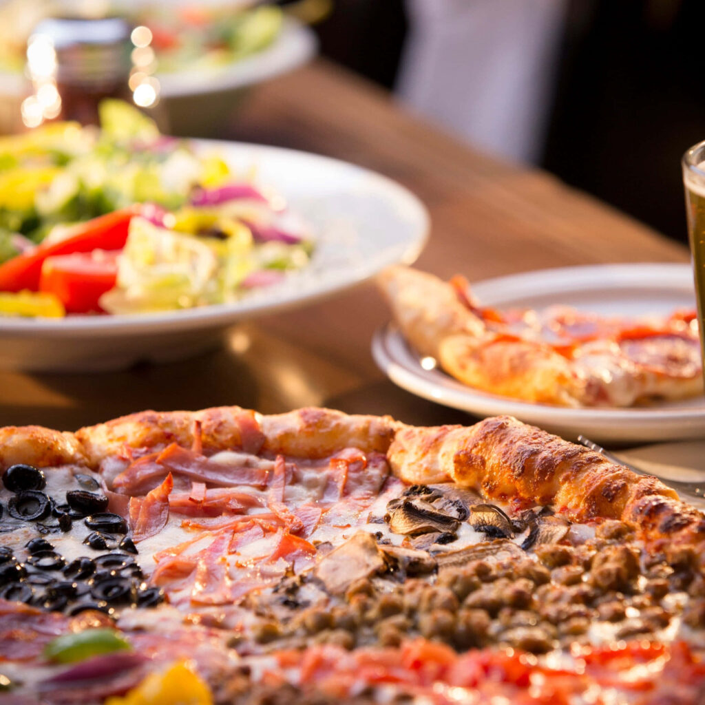 Delicious Pizza & Fresh Salad: Inviting Dining Atmosphere Wallpaper