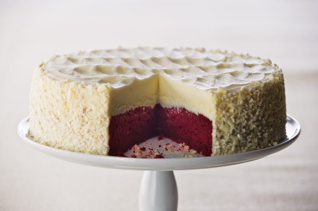 Elegant Layered Red Velvet Cheesecake: Creamy Slice on Pedestal Wallpaper
