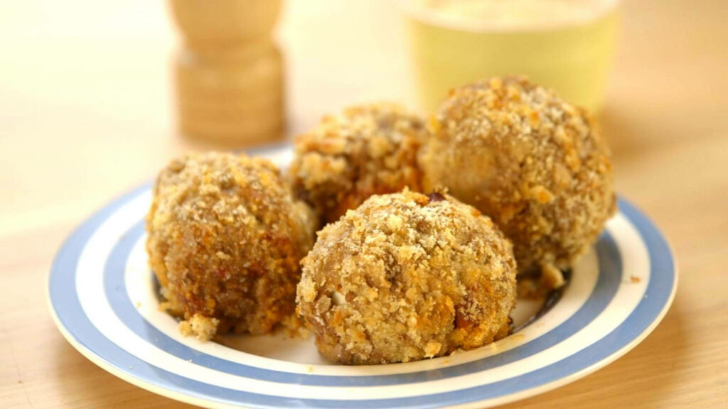 Delicious Scotch Eggs on Striped Plate: A Tasty British Delight Wallpaper