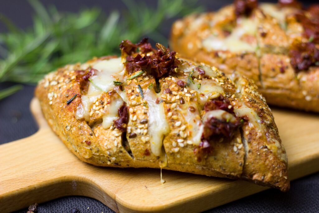 Close-Up of Cheese & Sun-Dried Tomato Sesame Bread on Wooden Board Wallpaper