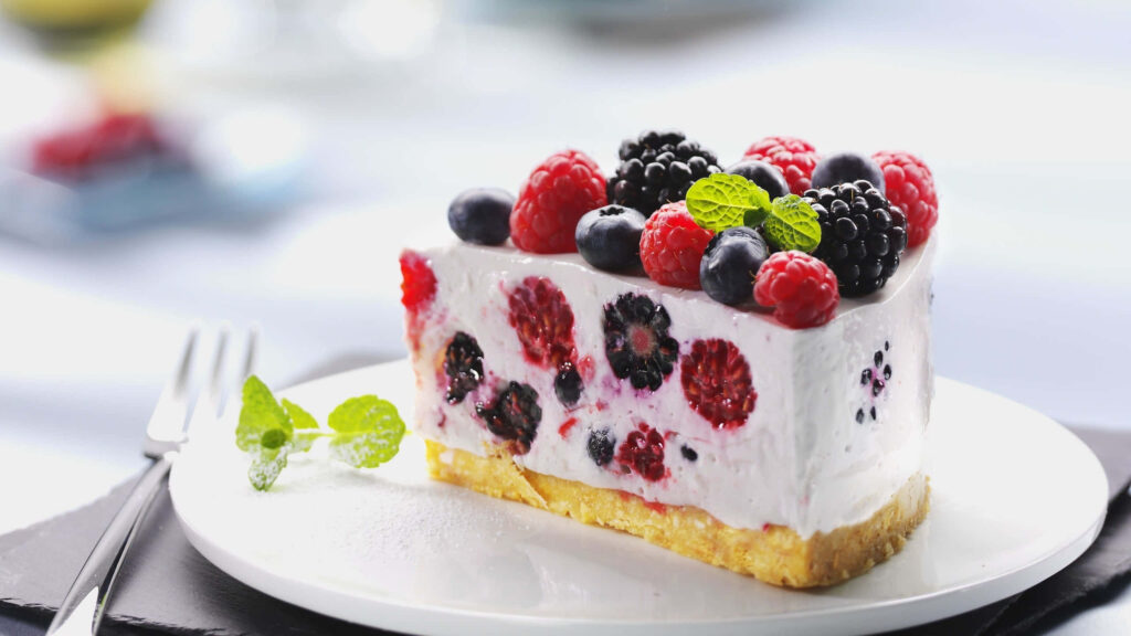 Delightful Spring Dessert Array: A Tempting Medley of Vibrant Macarons, Fresh Fruit Tarts, and Exquisite Cupcakes, Displayed on a Charming Rustic Table, Beckoning to be Indulged Wallpaper