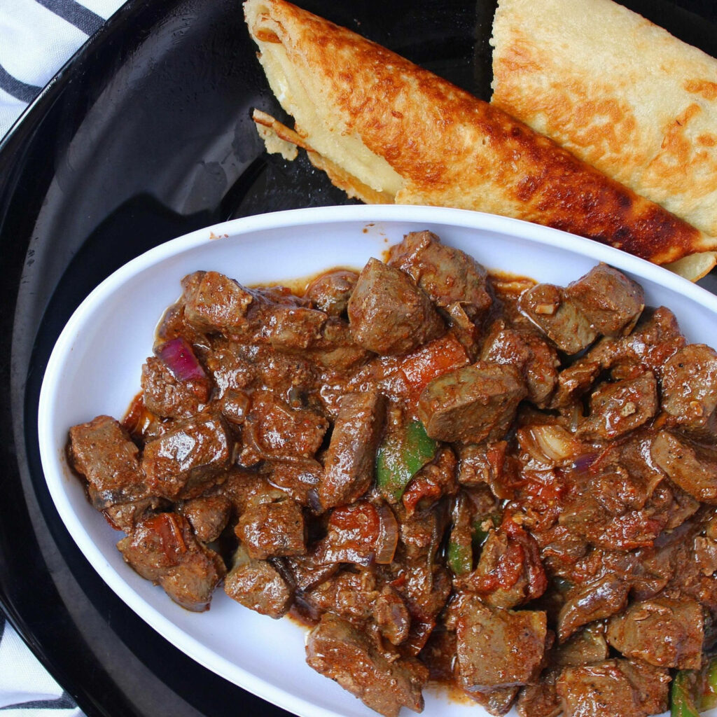 Stir-fried beef liver with colorful vegetables and golden pita bread on dark plate wallpaper