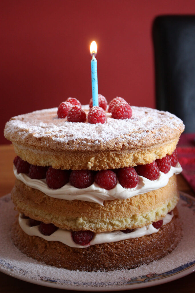 Festive Three-Layer Sponge Cake with Raspberries & Blue Candle Wallpaper