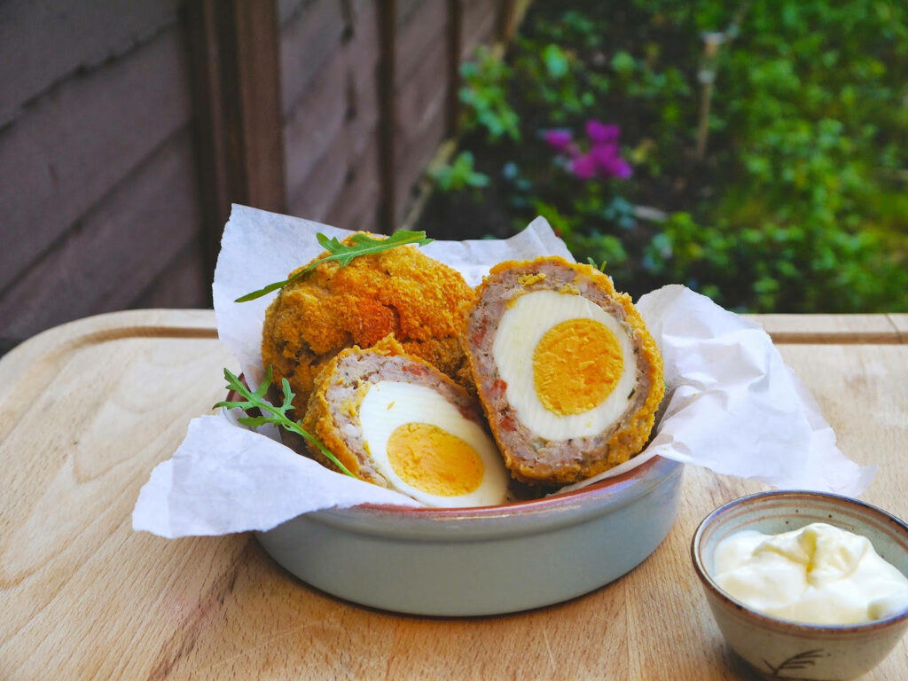 Delicious British Scotch Eggs with Dip on Rustic Garden Table Wallpaper