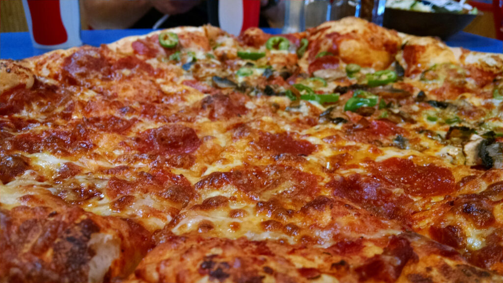 Two flavored Domino's Pizza with pepperoni and veggie toppings on golden melted cheese crust Wallpaper