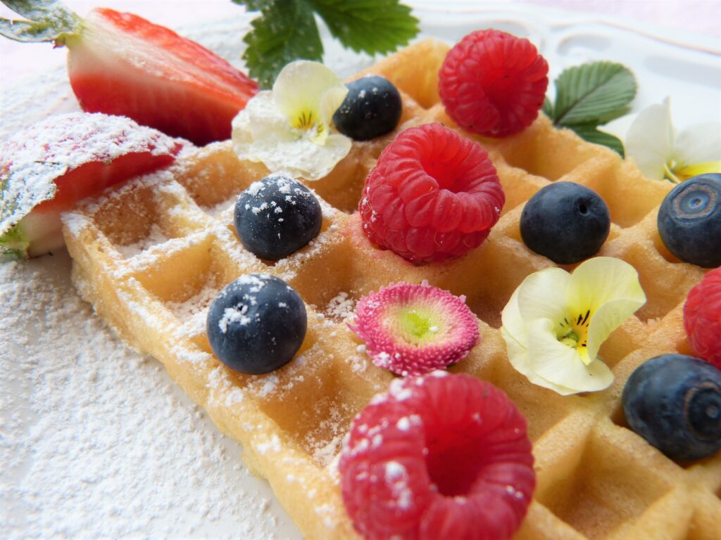 Delicious Waffle Close-Up: Raspberries, Blueberries & Flowers Wallpaper