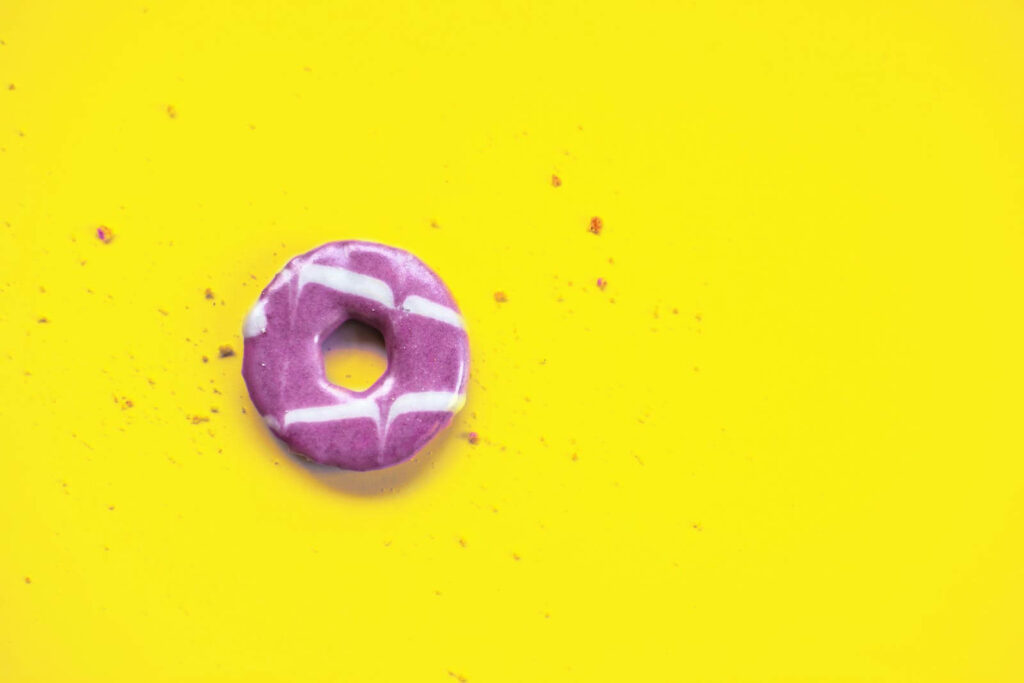 Delectable Delight: Decadent Donut with Lavish Frosting on Sunny Delight Background Wallpaper