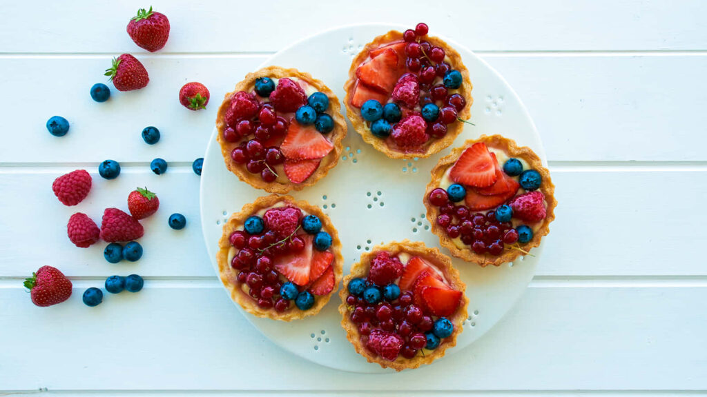 Five Indulgent Mini Tarts with Fresh Fruits on a Beautiful Platter Wallpaper