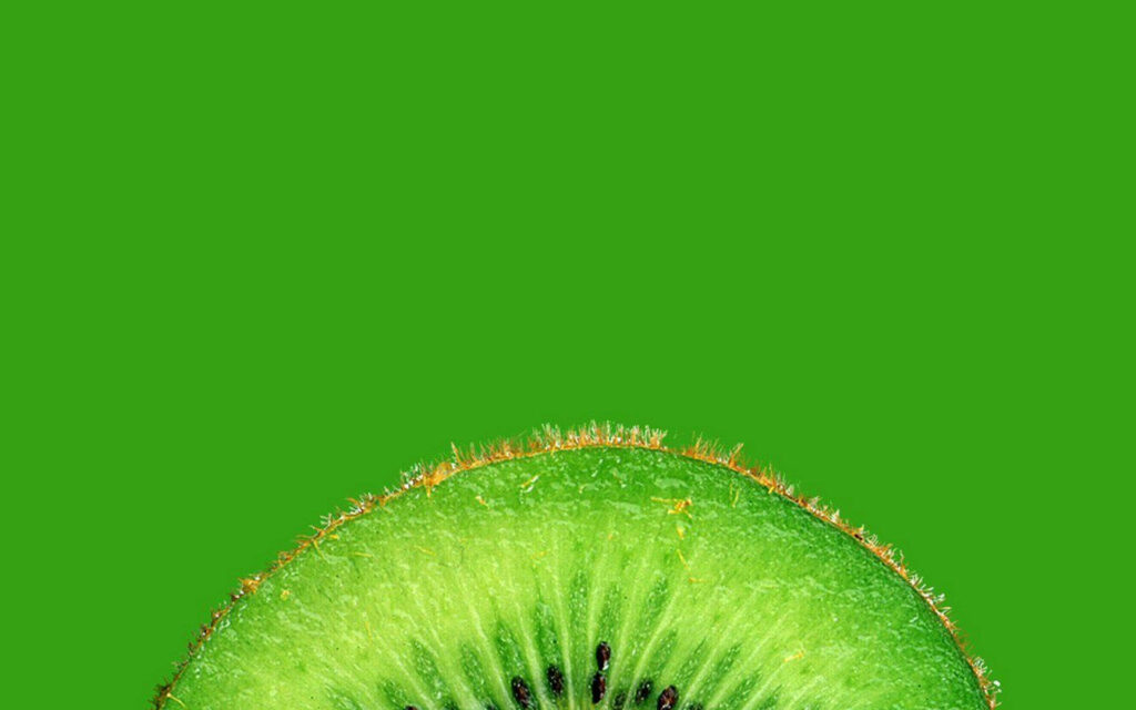 Serenity in a Single Slice: Captivating Kiwi against Lush Green Backdrop Wallpaper