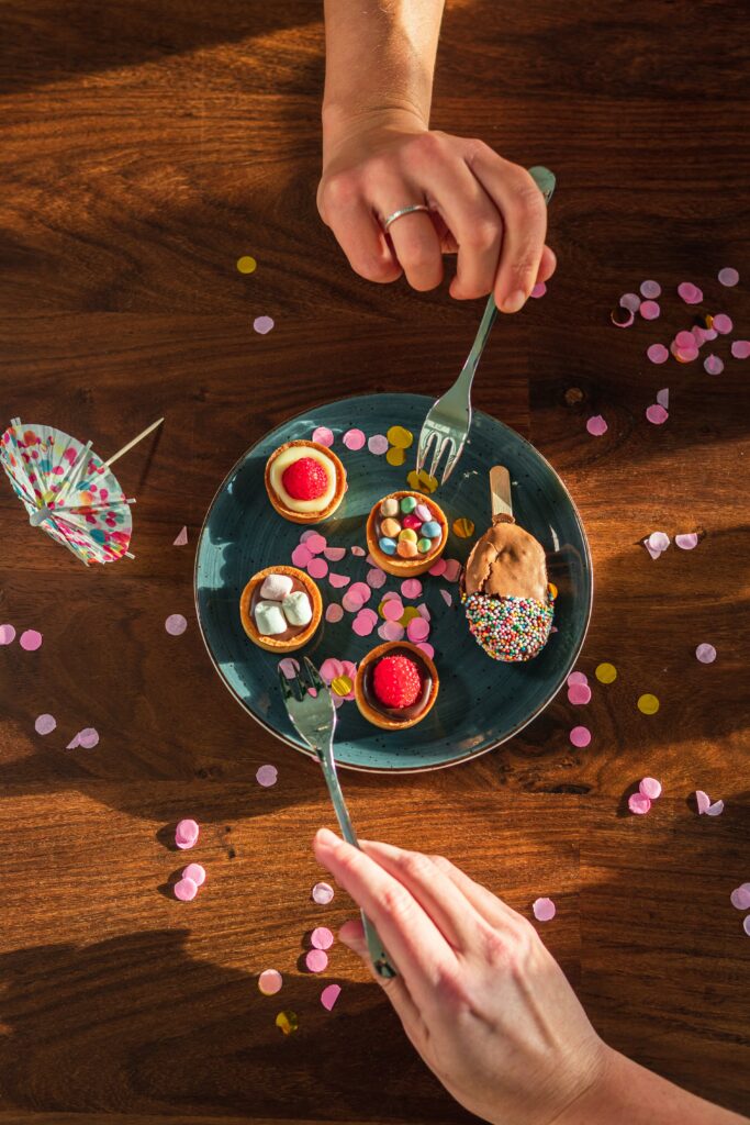Colorful Dessert Arrangement Wallpaper: Hands Reaching for Treats