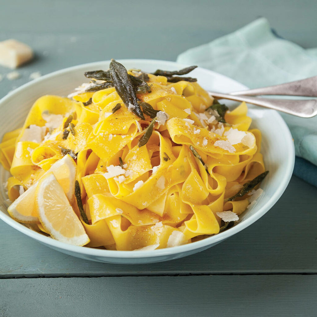 Delightful Pasta Wallpaper: Golden Bowl with Sage & Lemon Wedges