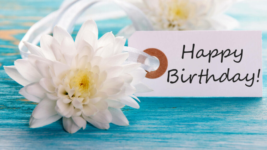 A Delightfully Festive Happy Birthday with Charming Floral Accents on a Teal Wooden Background Wallpaper