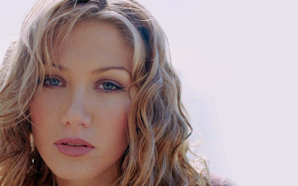 Delta Goodrem close-up portrait with soft natural light highlighting wavy blonde hair serene background Wallpaper