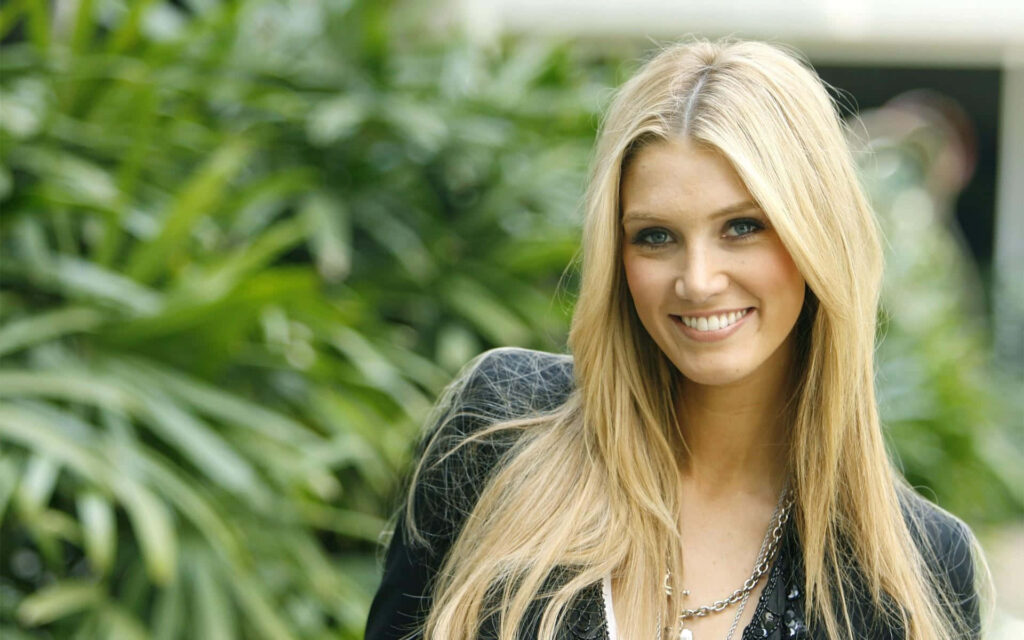 Delta Goodrem outdoors with blonde hair and bright smile against lush green natural background wallpaper