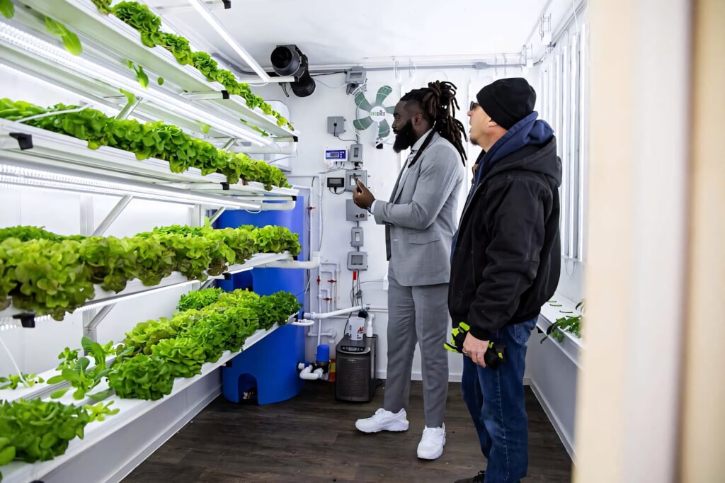 Demario Davis exploring indoor hydroponic farm with vertical green vegetables sustainable urban agriculture Wallpaper